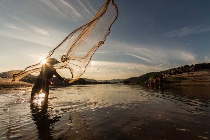 Premium Photo  Fisherman casting fishing net in lake during sunset